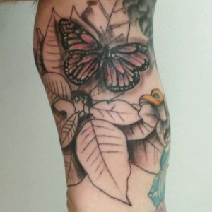 Close up of butterfly tattoo within floral sleeve