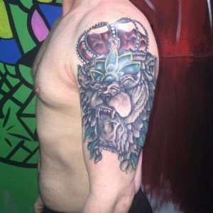 Lion with crown bicep tattoo